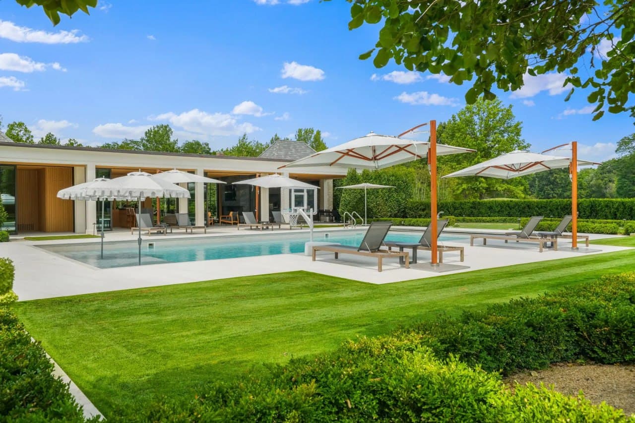 Modern pool patio with cantilever umbrellas and hedged garden surround.