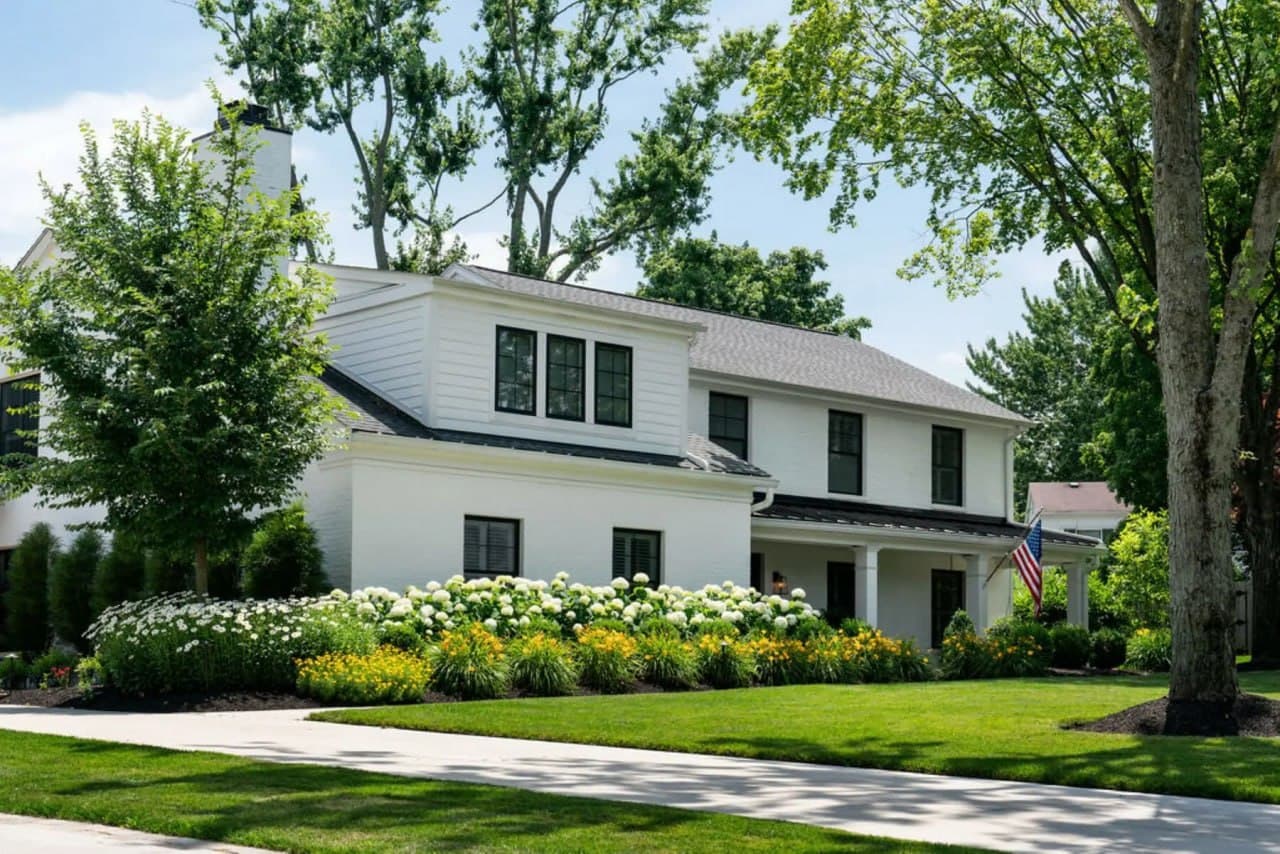 White brick colonial with annabelle hydrangeas and daylily border.