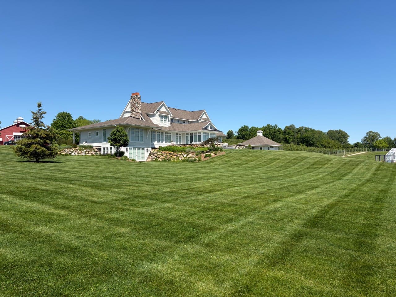 Hilltop residence above a wide striped lawn under a clear summer sky.
