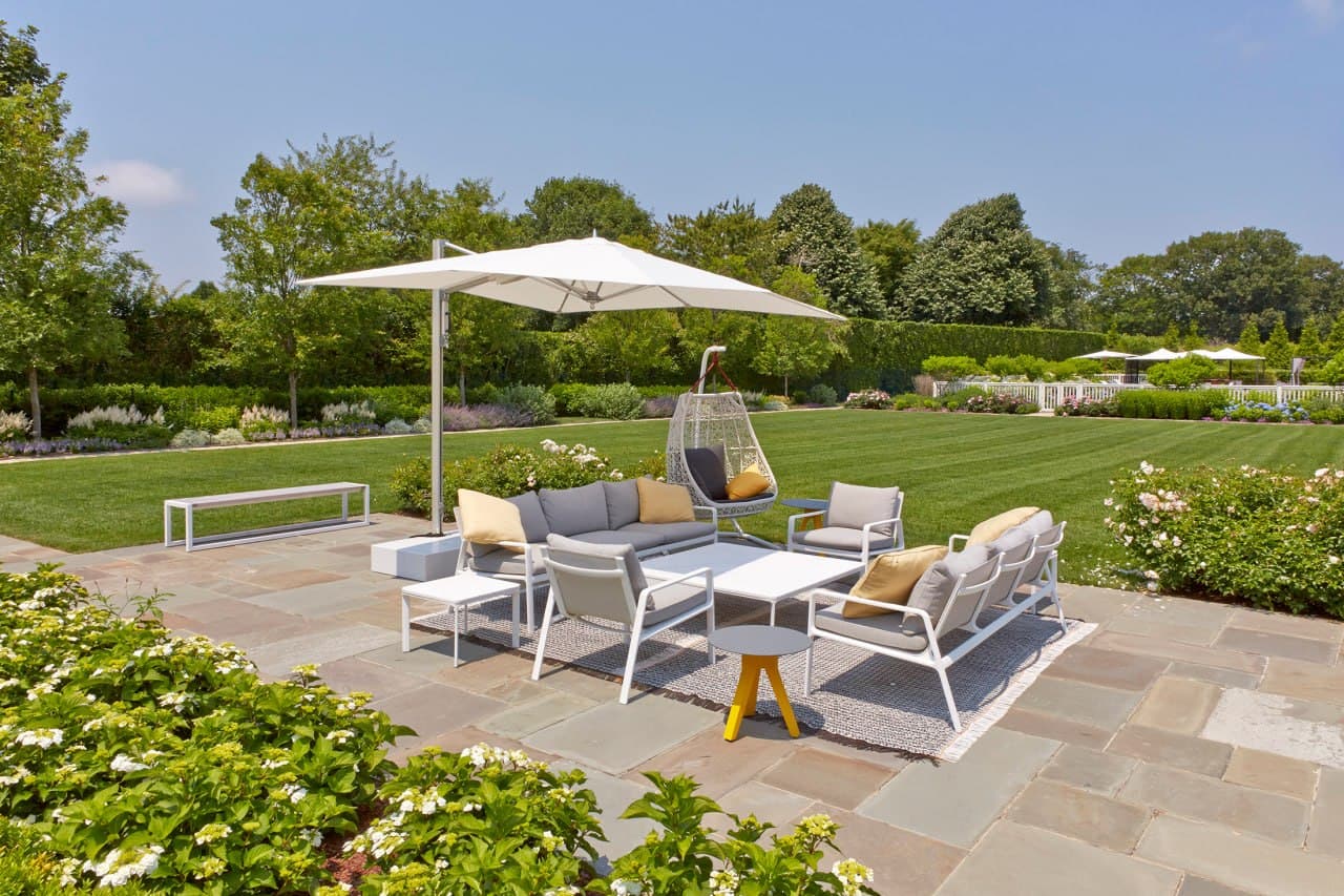 Bluestone patio with white outdoor furniture set against a kept lawn.